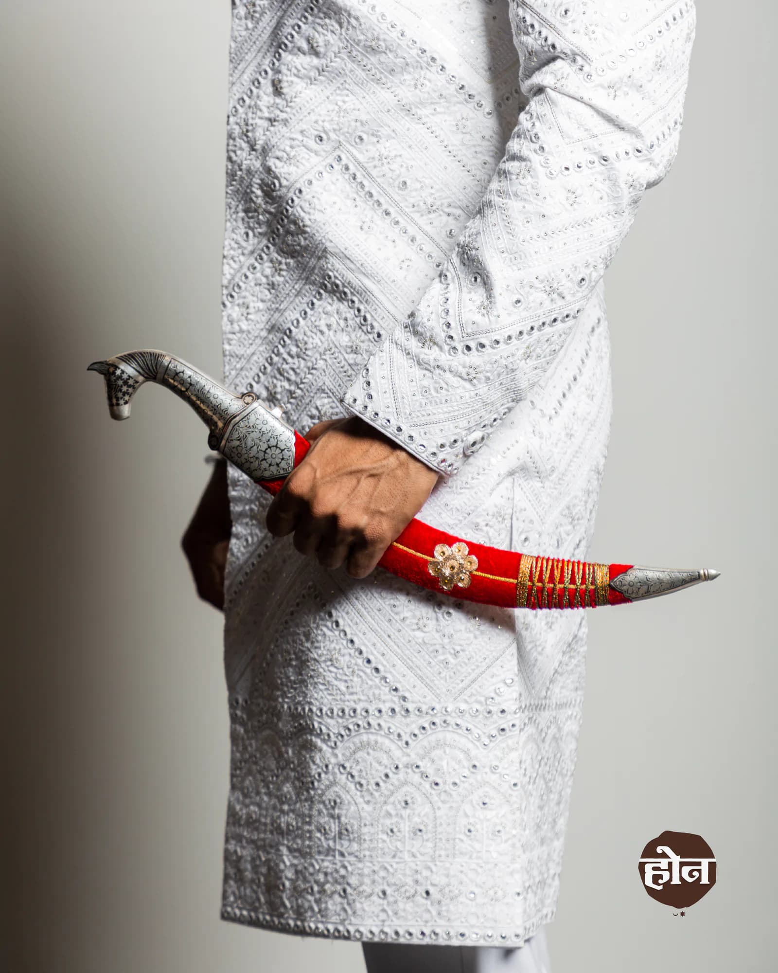 Detail of an embroidered sherwani sleeve and ceremonial sword